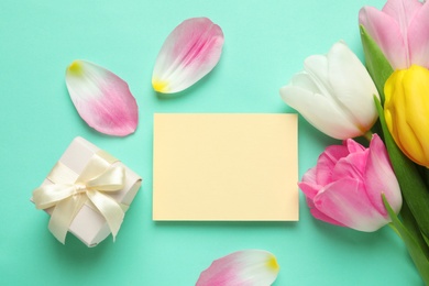 Photo of Flat lay composition of tulips and blank card on color background, space for text. International Women's Day