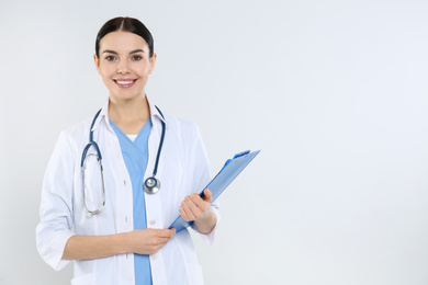 Photo of Portrait of young doctor with stethoscope and clipboard on white background