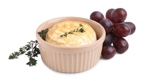 Tasty baked camembert in bowl, grapes and thyme on white background