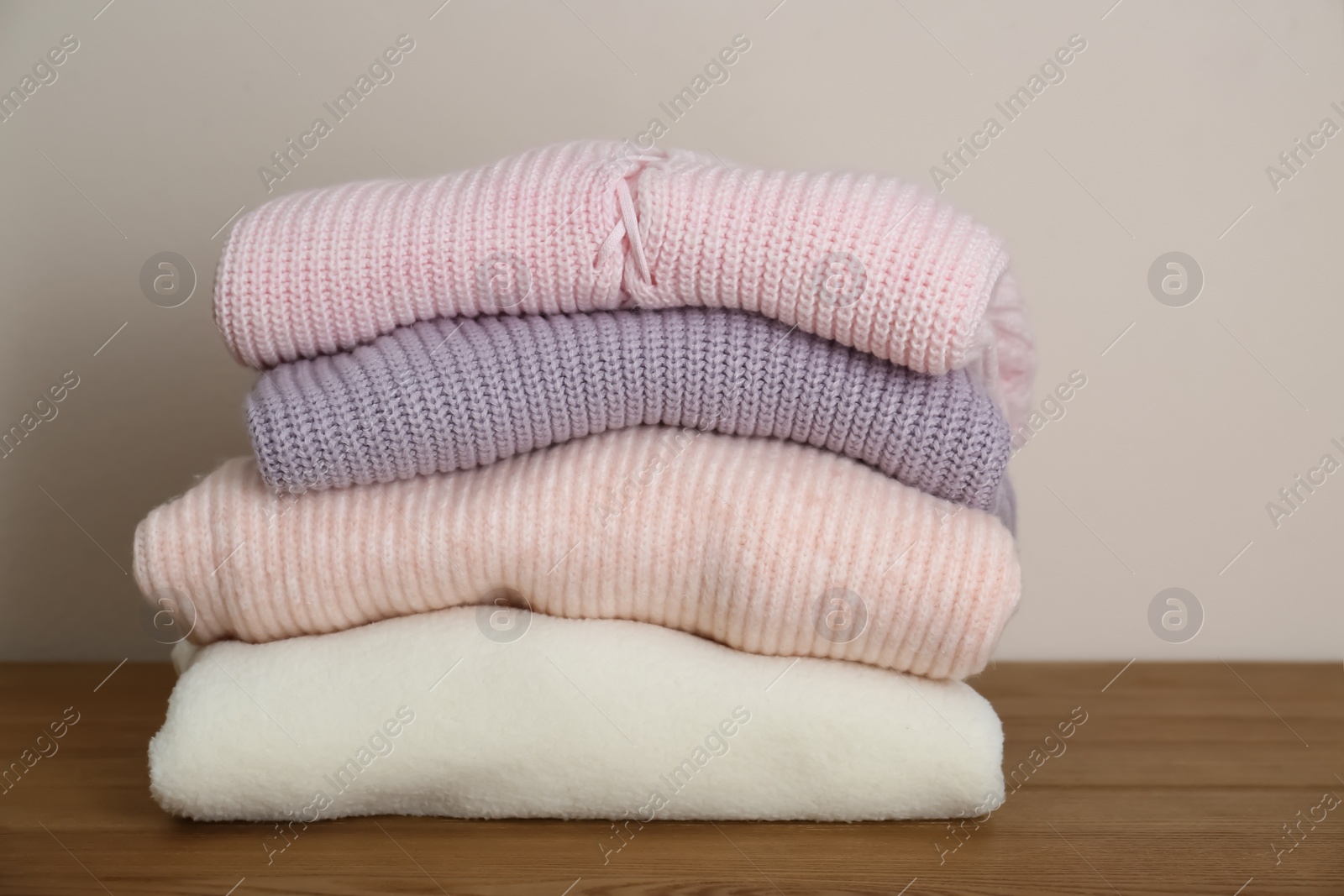 Photo of Stack of knitted sweaters on wooden table