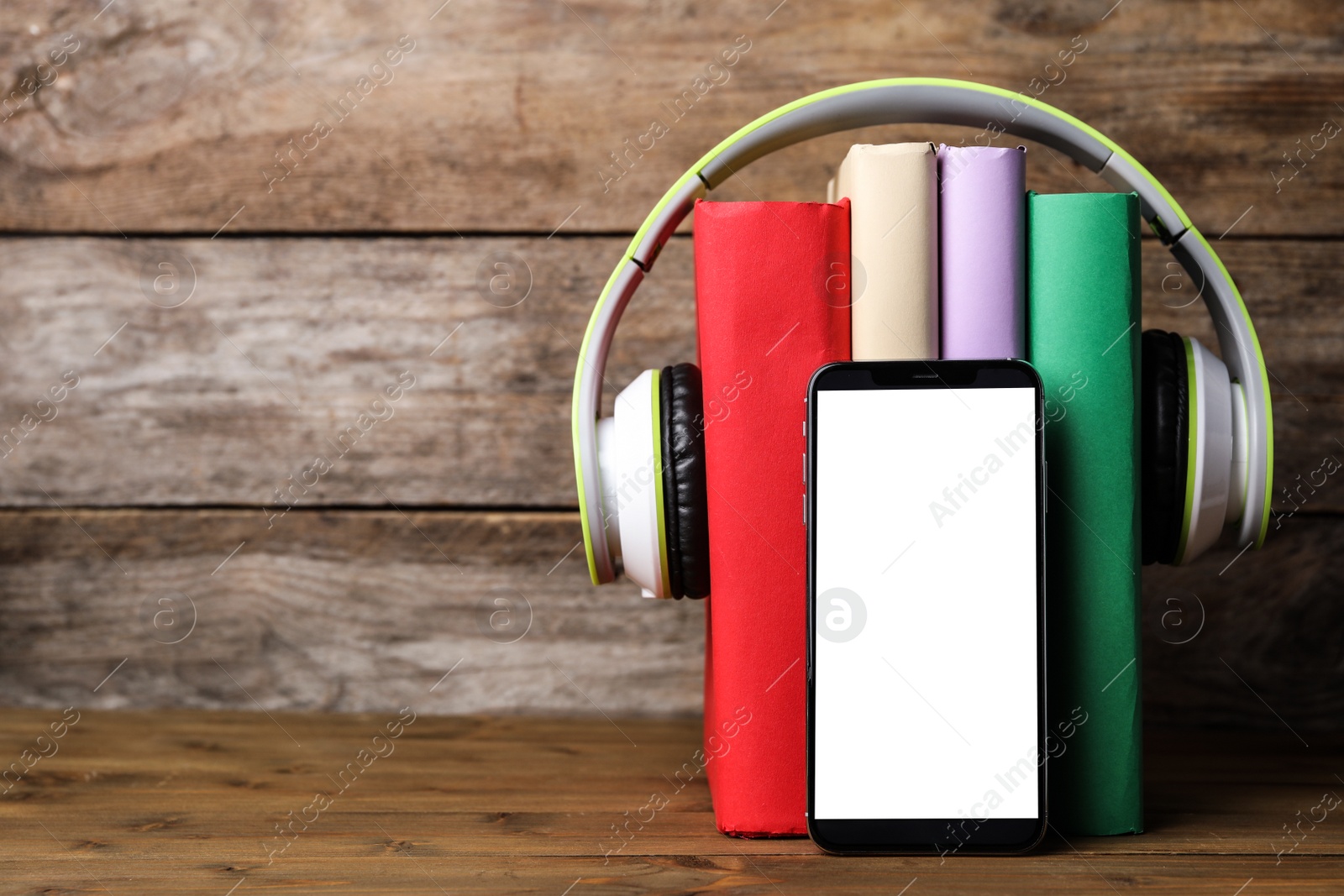 Photo of Books with modern headphones and smartphone on wooden table. Space for text