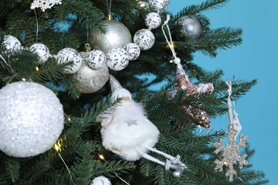 Photo of Beautiful Christmas tree with decor on light blue background, closeup