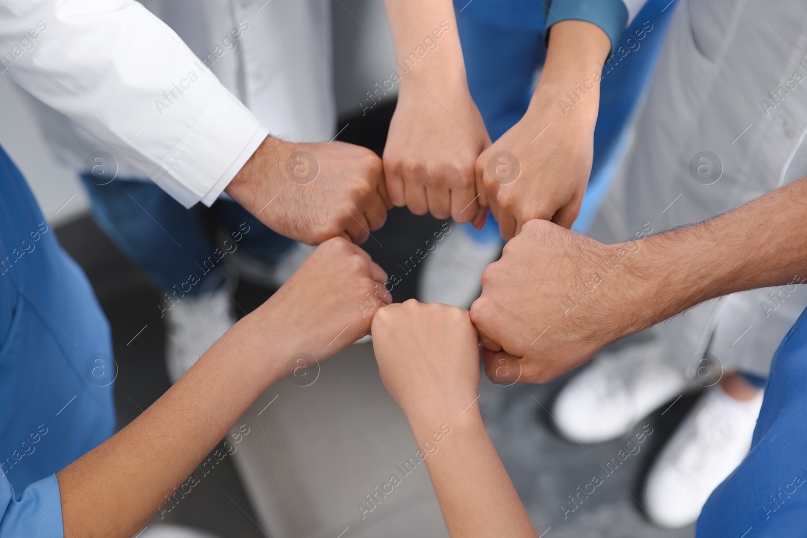 Photo of Team of medical doctors putting hands together indoors, closeup