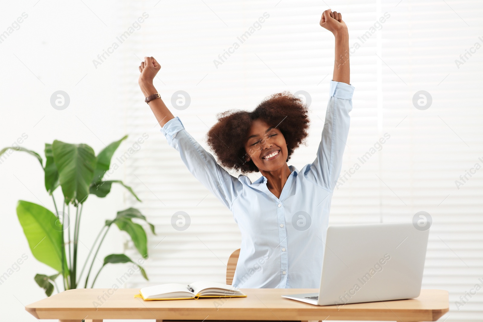 Photo of Smiling African American woman at wooden table indoors