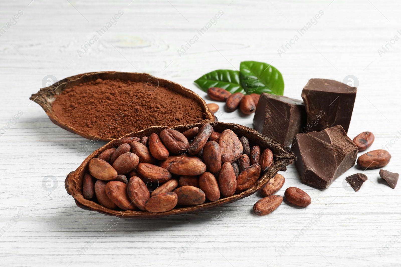 Photo of Cocoa pods of beans and powder with chocolate on white wooden table