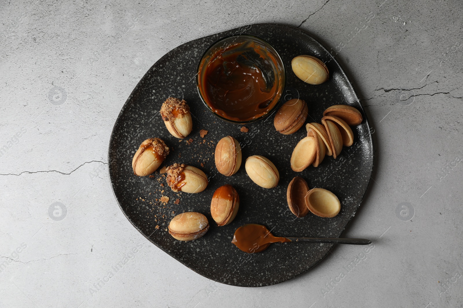 Photo of Delicious walnut shaped cookies with condensed milk on grey table, top view