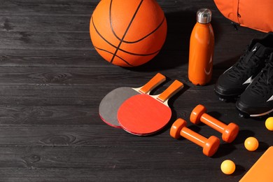 Many different sports equipment on dark grey wooden table, space for text