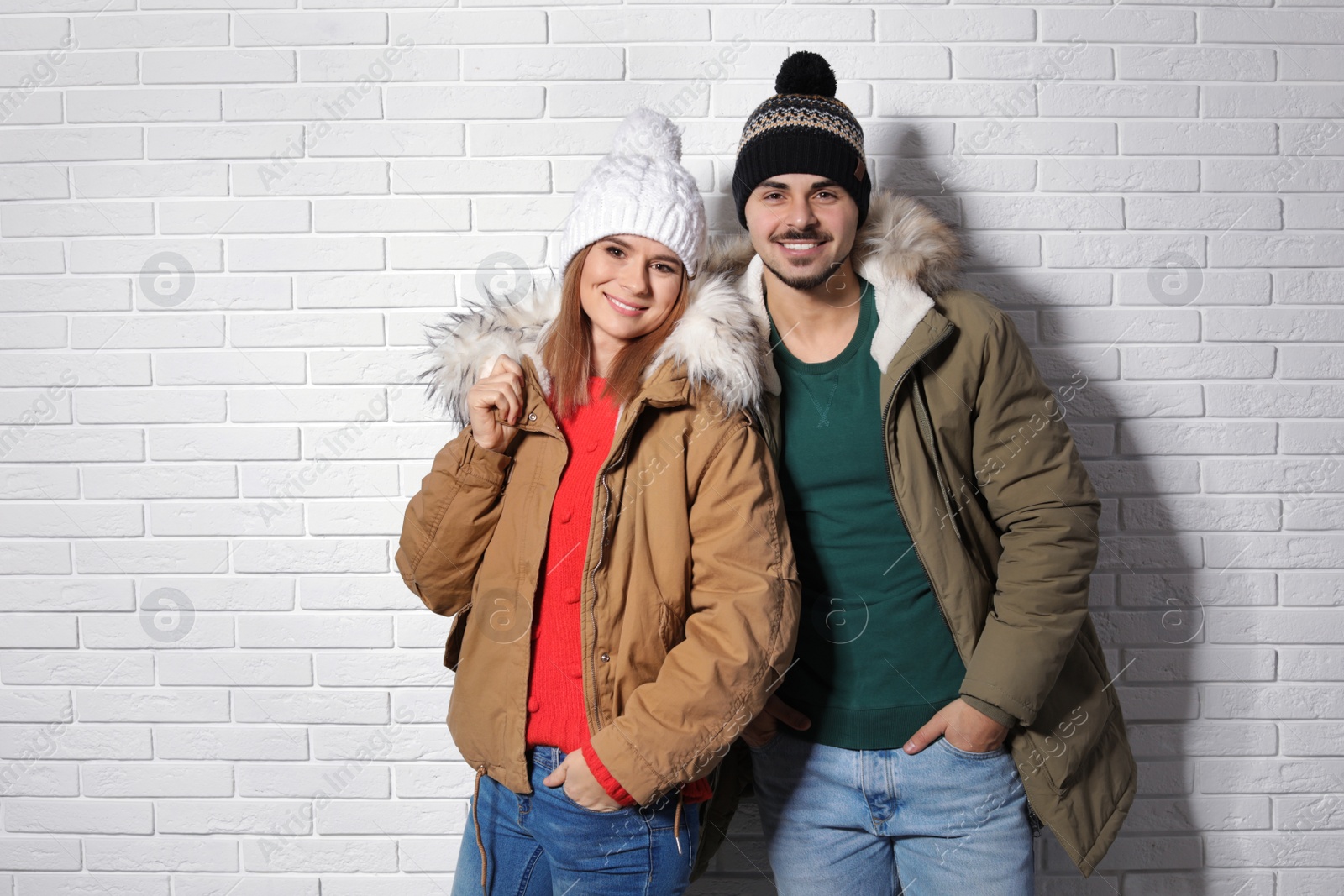 Photo of Young couple wearing warm clothes against brick wall. Ready for winter vacation