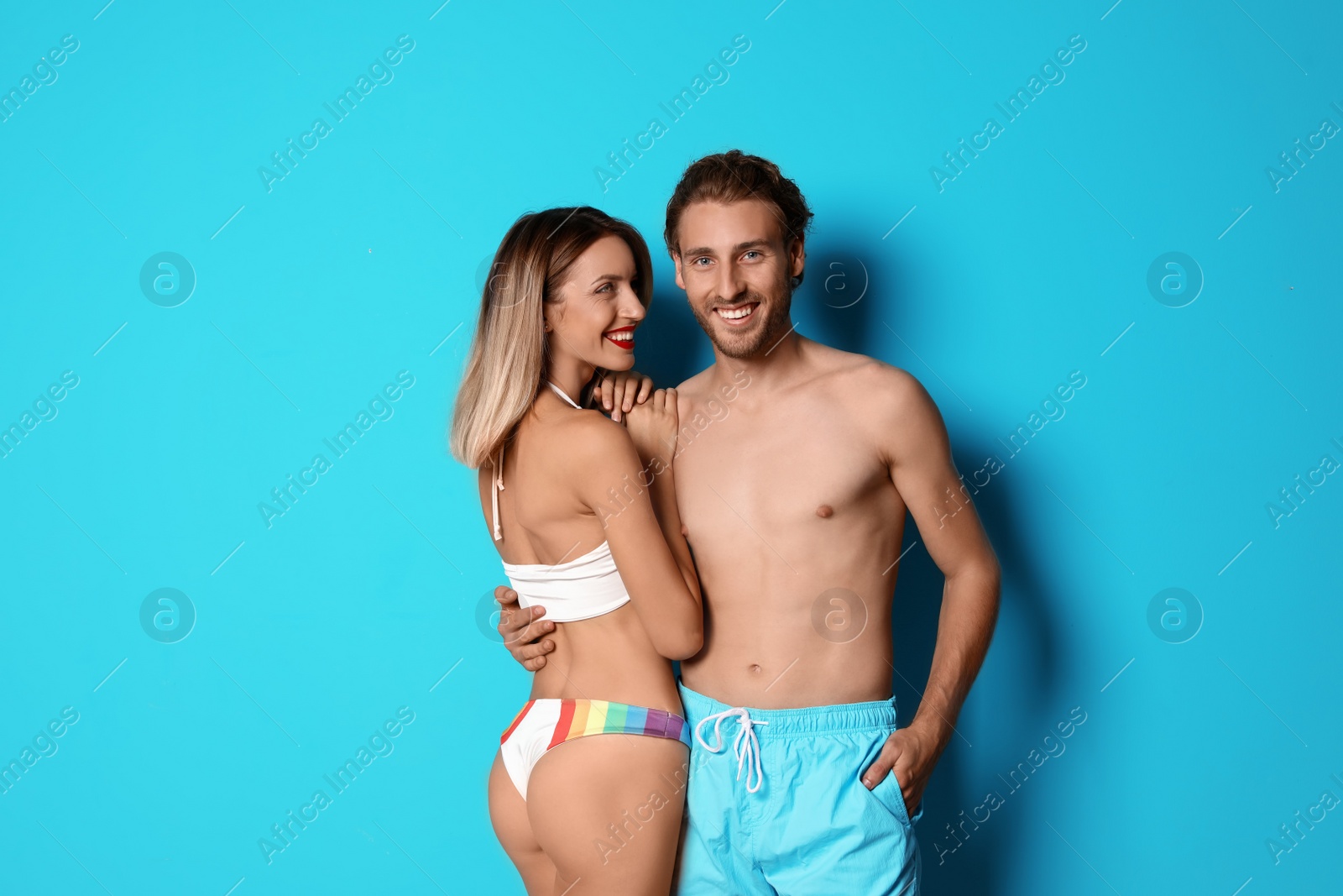 Photo of Happy young couple in beachwear on color background