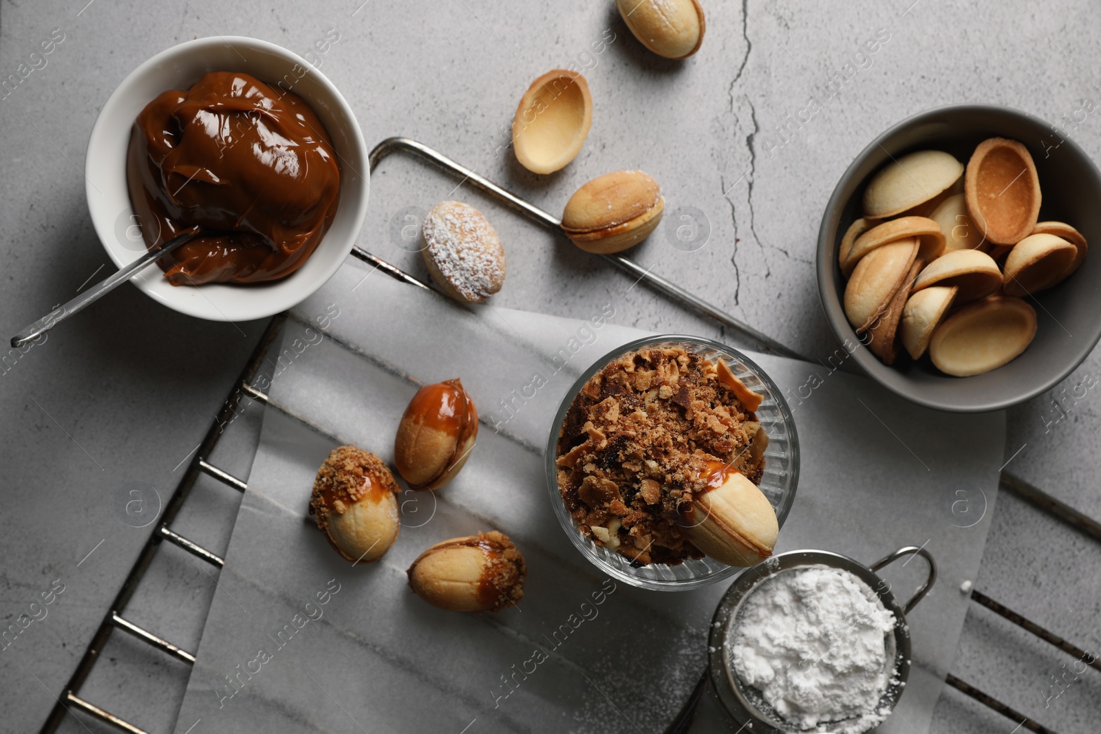 Photo of Delicious walnut shaped cookies with condensed milk on grey table, flat lay