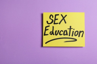 Photo of Note with phrase "SEX EDUCATION" on violet background, top view