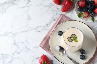 Photo of Tasty yogurt in glass and berries on white marble table, flat lay. Space for text