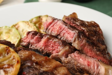 Photo of Delicious grilled beef steak and zucchini on plate, closeup