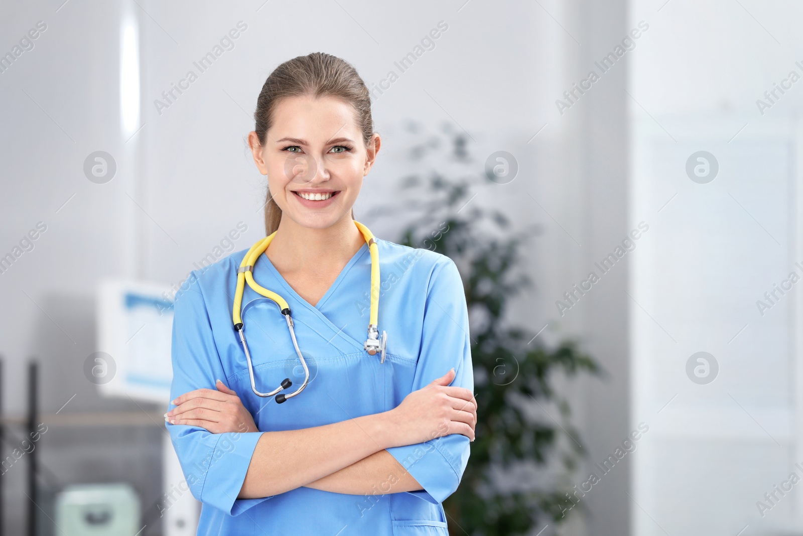 Photo of Portrait of young medical assistant with stethoscope in hospital. Space for text