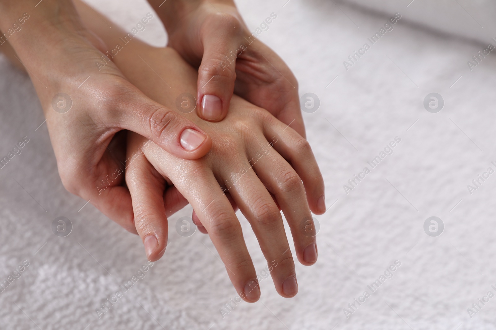 Photo of Woman receiving hand massage on soft towel, closeup