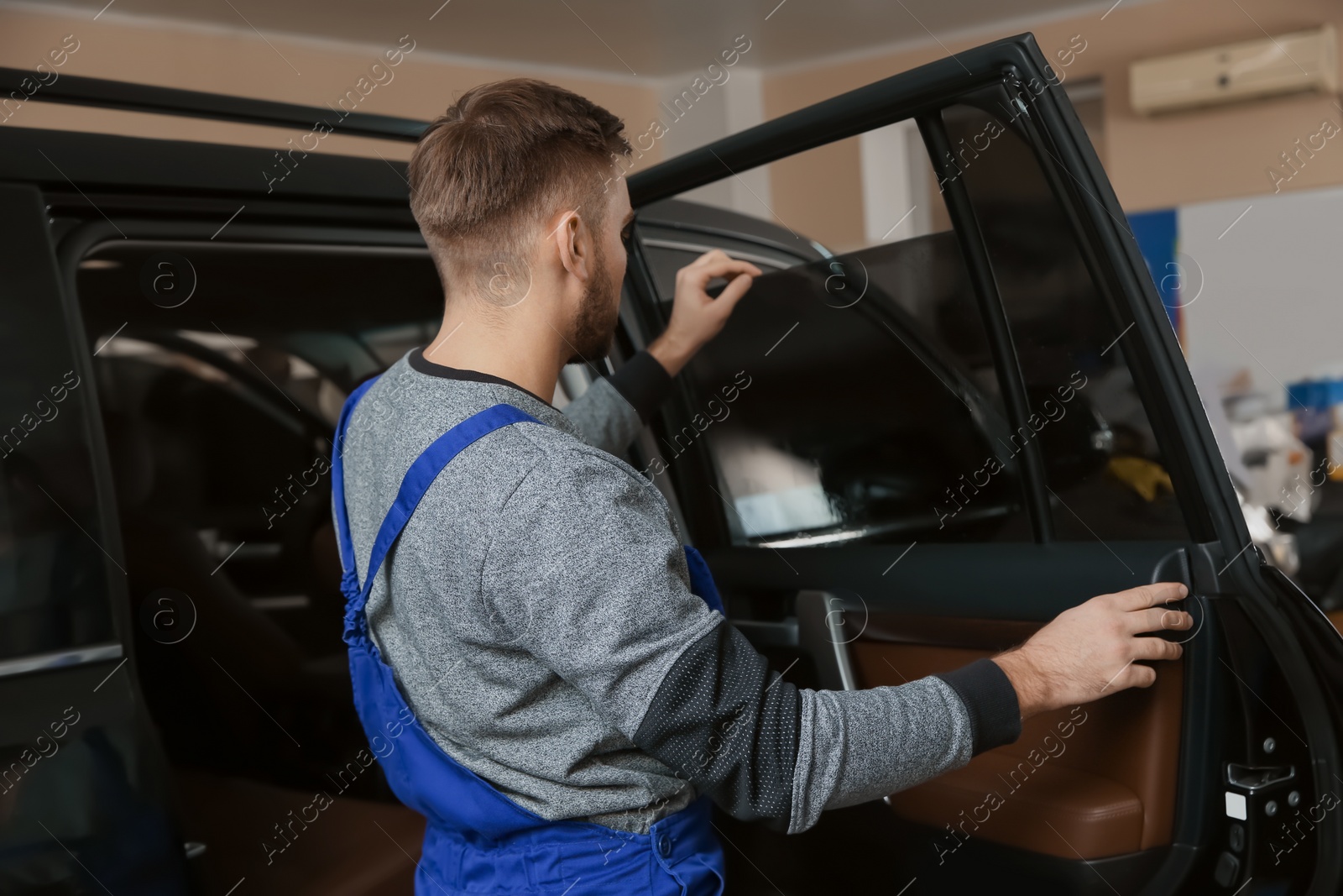 Photo of Skilled worker checking tinted car window in shop
