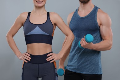 Photo of Athletic people with dumbbells on grey background, closeup