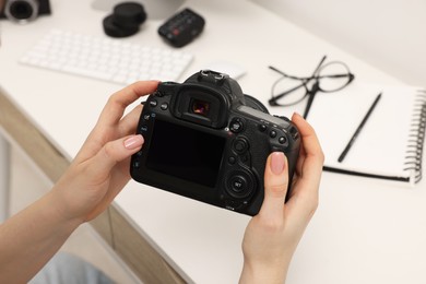 Photographer with camera at white table indoors, closeup