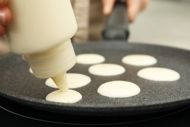 Woman cooking cereal pancake on frying pan, closeup