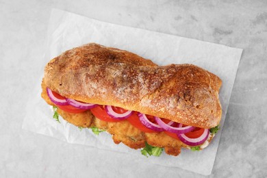 Delicious sandwich with schnitzel on grey table, top view