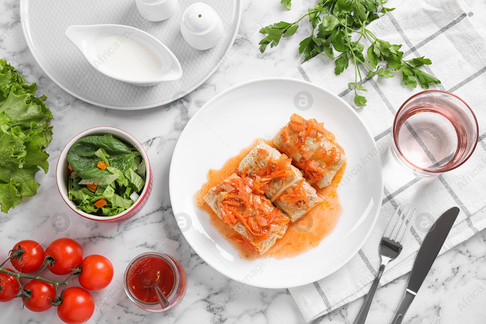 Photo of Delicious cabbage rolls served on white marble table, flat lay