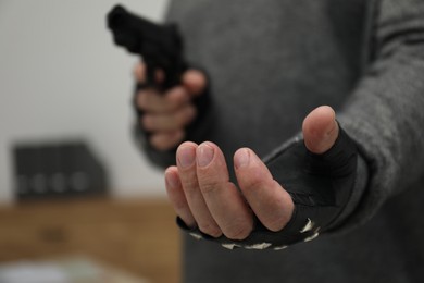 Dangerous criminal with gun indoors, closeup. Armed robbery