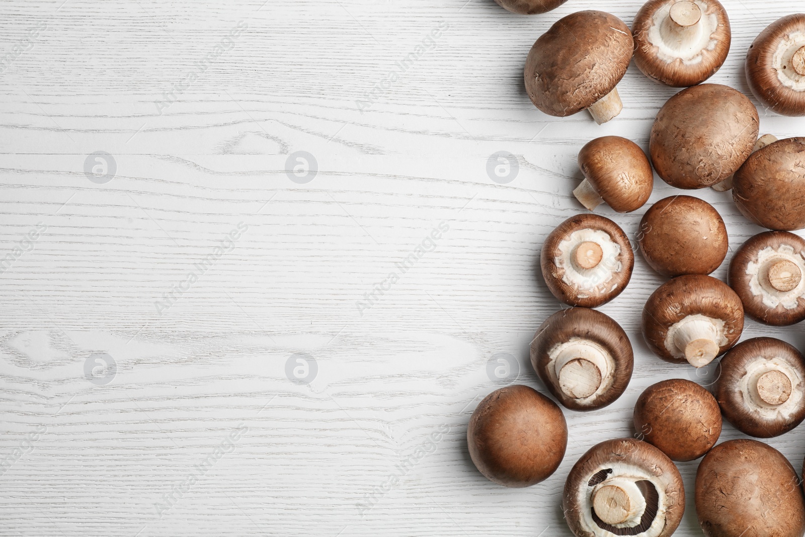 Photo of Flat lay composition with fresh champignon mushrooms on wooden table. Space for text