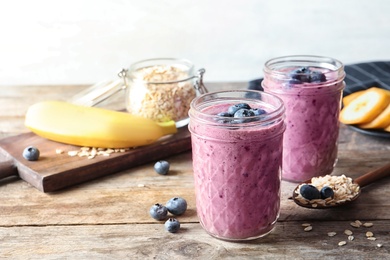 Photo of Jars with blueberry smoothies on wooden table