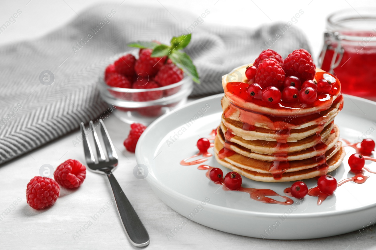 Photo of Delicious pancakes with fresh berries and syrup on white table