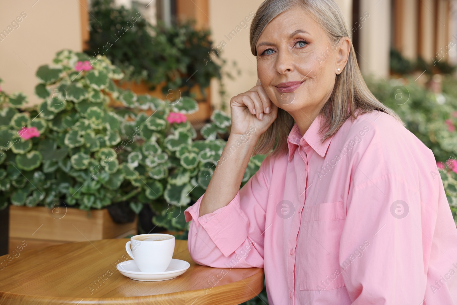 Photo of Portrait of beautiful senior woman with cup of coffee at table in outdoor cafe