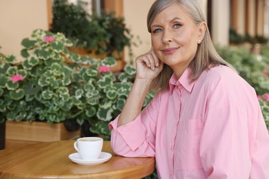 Photo of Portrait of beautiful senior woman with cup of coffee at table in outdoor cafe