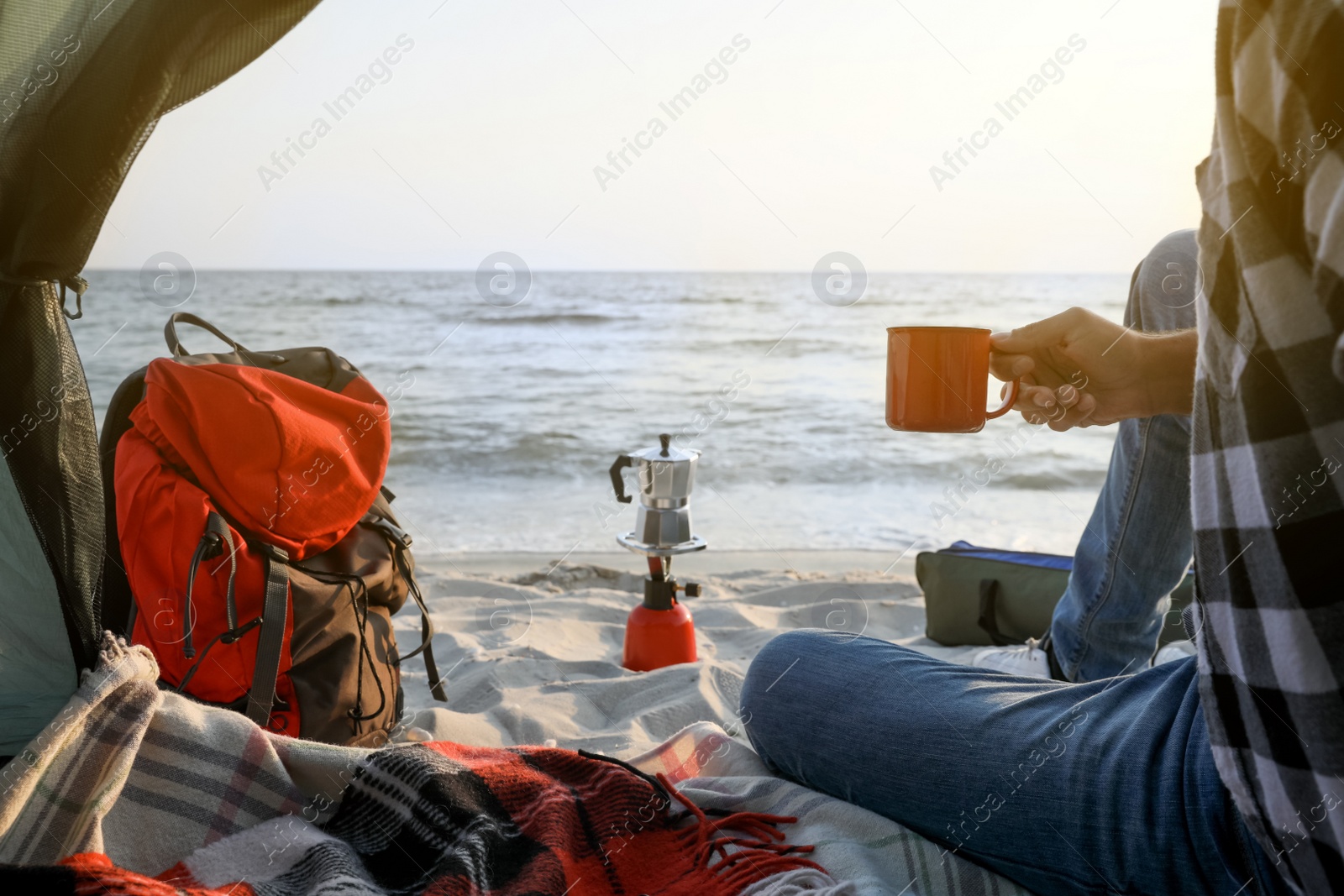 Photo of Man with cup of hot drink in camping tent, closeup