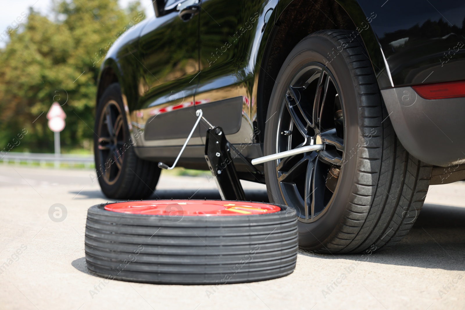 Photo of Tire puncture. New wheel near car on roadside outdoors