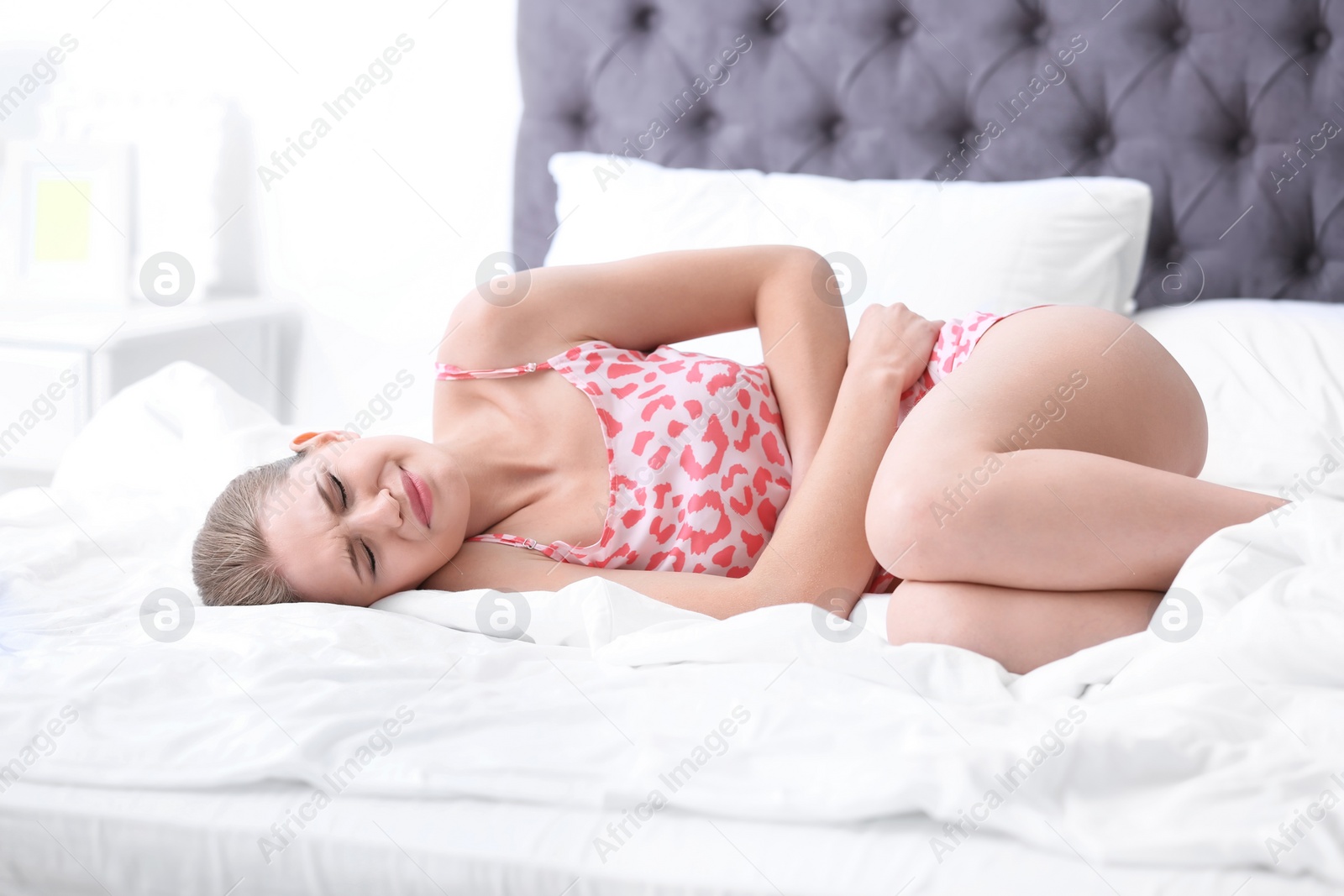 Photo of Young woman suffering from menstrual cramps at home. Gynecology