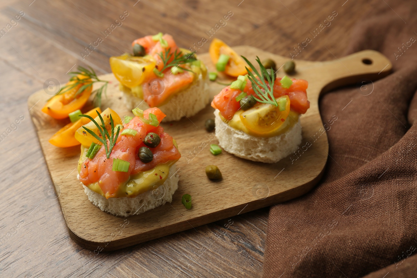 Photo of Tasty canapes with salmon served on wooden table, closeup