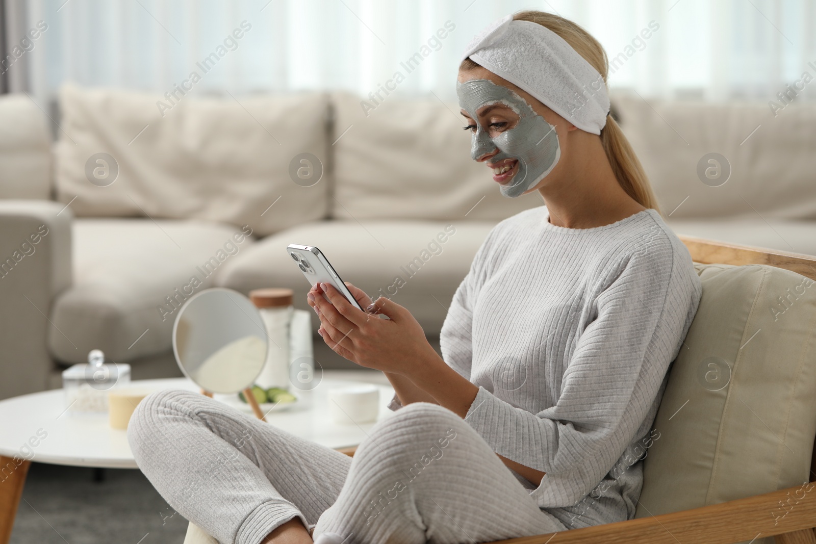 Photo of Young woman with face mask using smartphone at home, space for text. Spa treatments