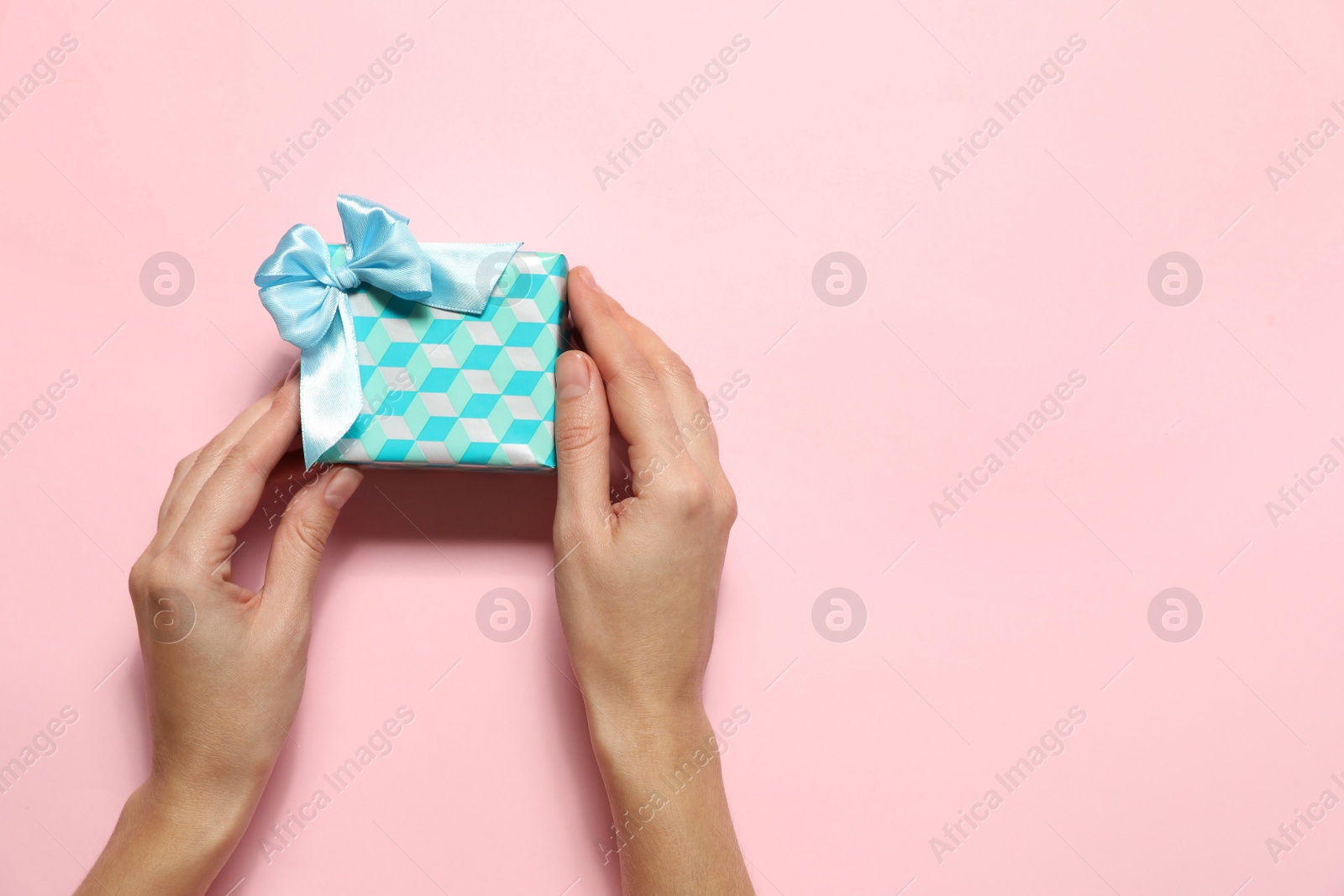 Photo of Woman holding Christmas gift on pink background, top view. Space for text
