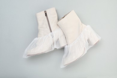 Photo of Women's boots in shoe covers on grey background, top view
