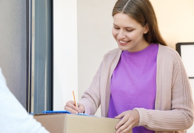 Woman receiving parcel from delivery service courier indoors