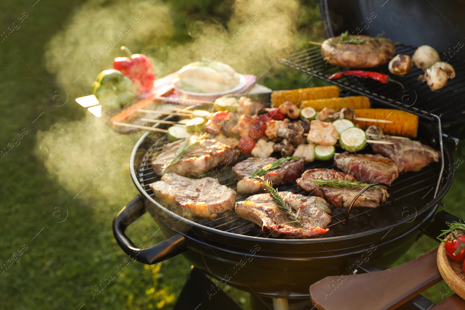 Photo of Cooking meat and vegetables on barbecue grill outdoors