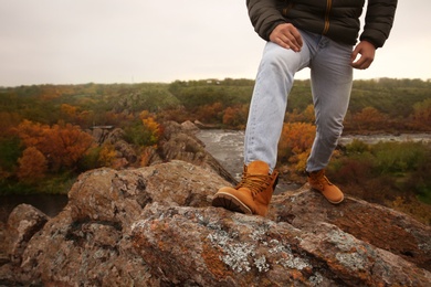 Man wearing stylish hiking boots on steep cliff, closeup