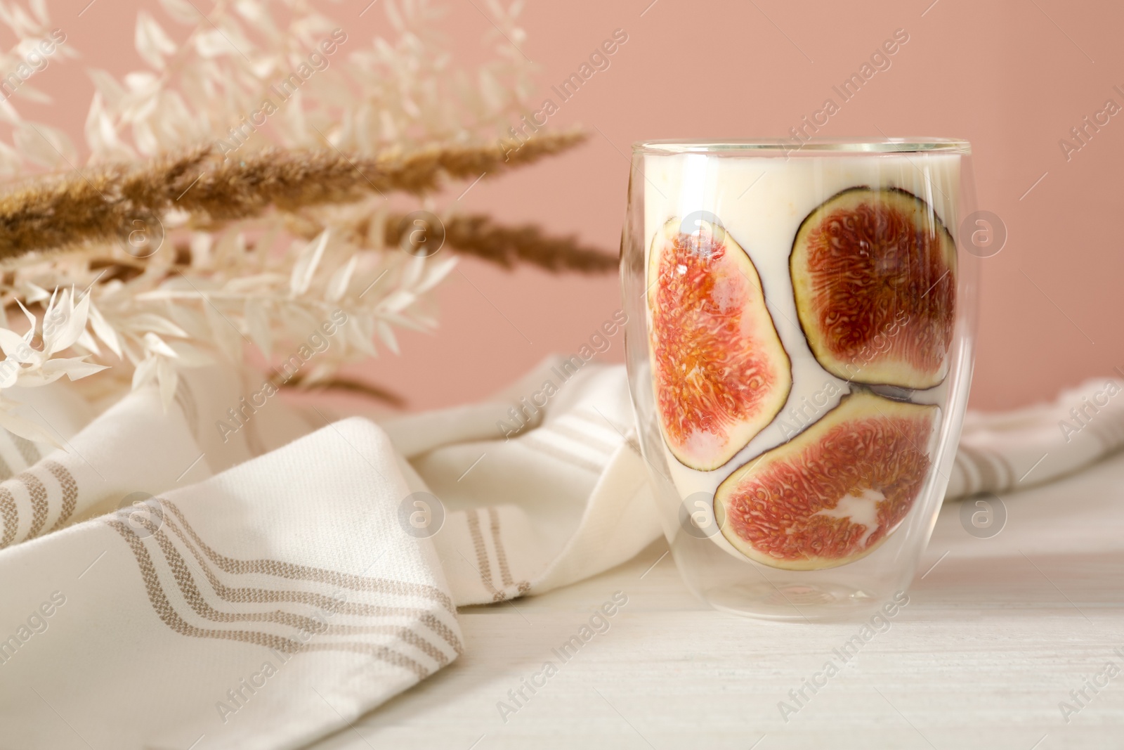 Photo of Delicious fig smoothie in glass on white wooden table