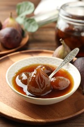 Photo of Bowl of tasty sweet fig jam on wooden table