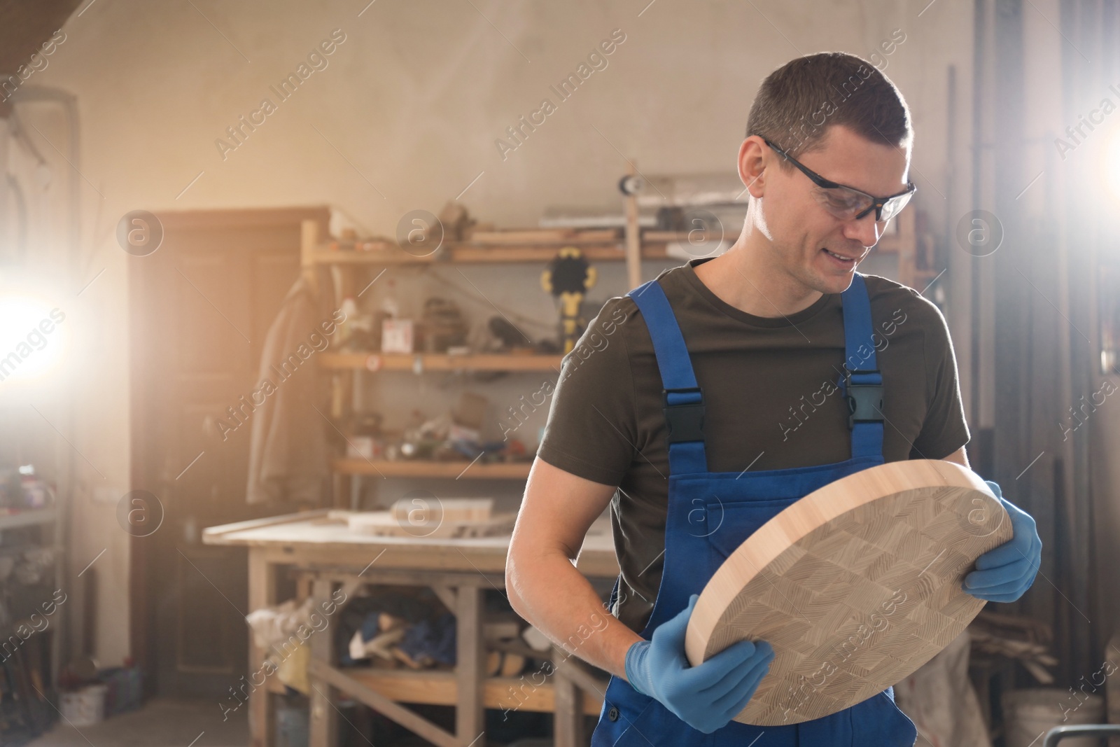 Photo of Professional carpenter with round piece of wood in workshop