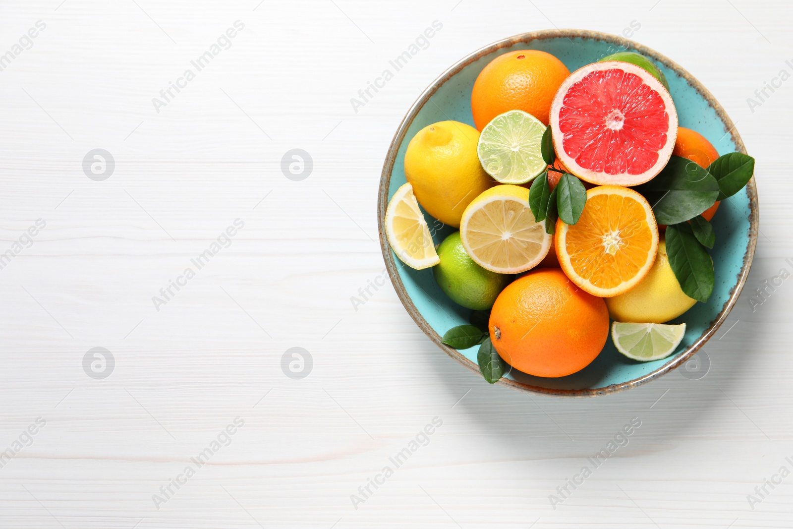 Photo of Different cut and whole citrus fruits on white wooden table, top view. Space for text