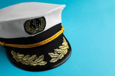 Photo of Peaked cap with accessories on light blue background, closeup. Space for text
