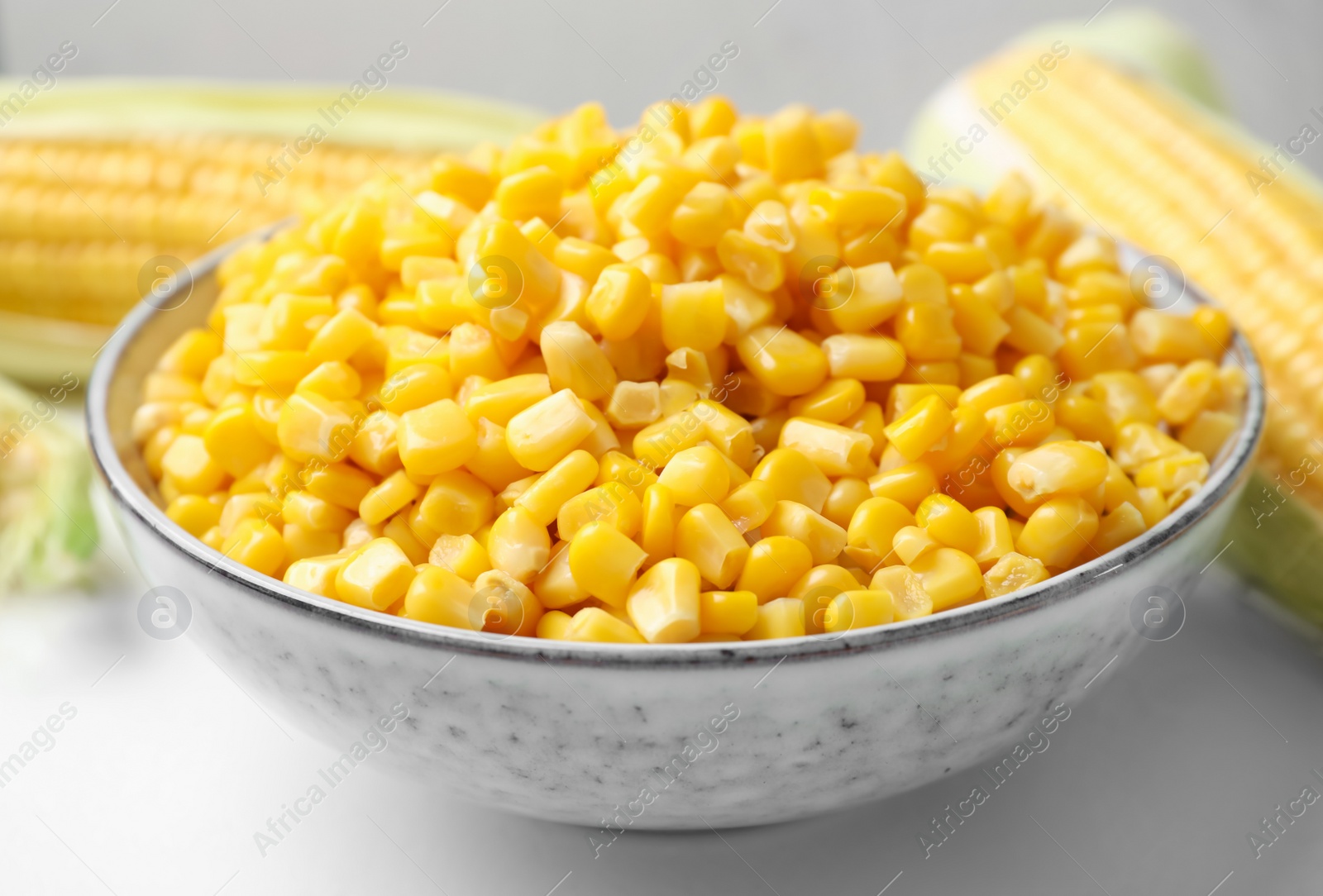 Photo of Bowl of preserved corn on white table, closeup