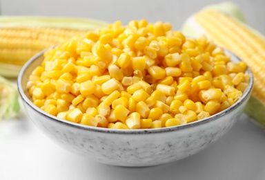 Photo of Bowl of preserved corn on white table, closeup