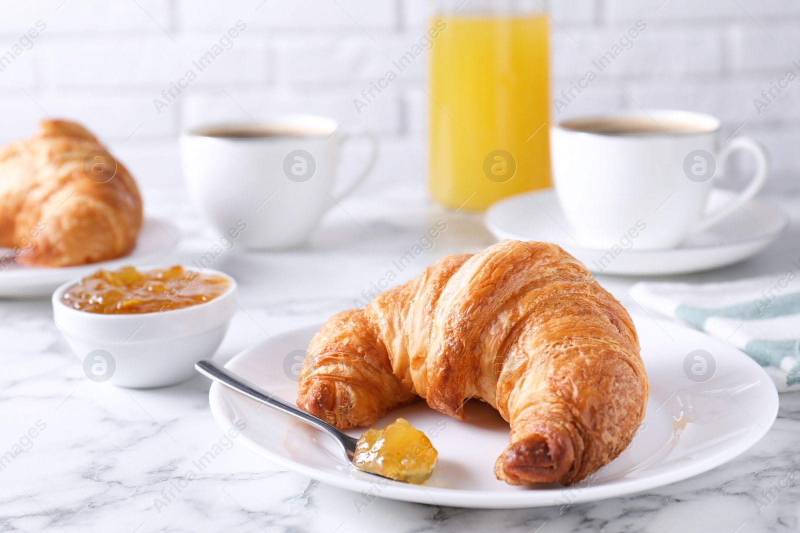 Photo of Tasty breakfast. Fresh croissant and jam on white marble table