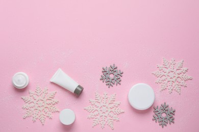 Flat lay composition with cosmetic products and snowflakes on pink background, space for text. Winter skin care